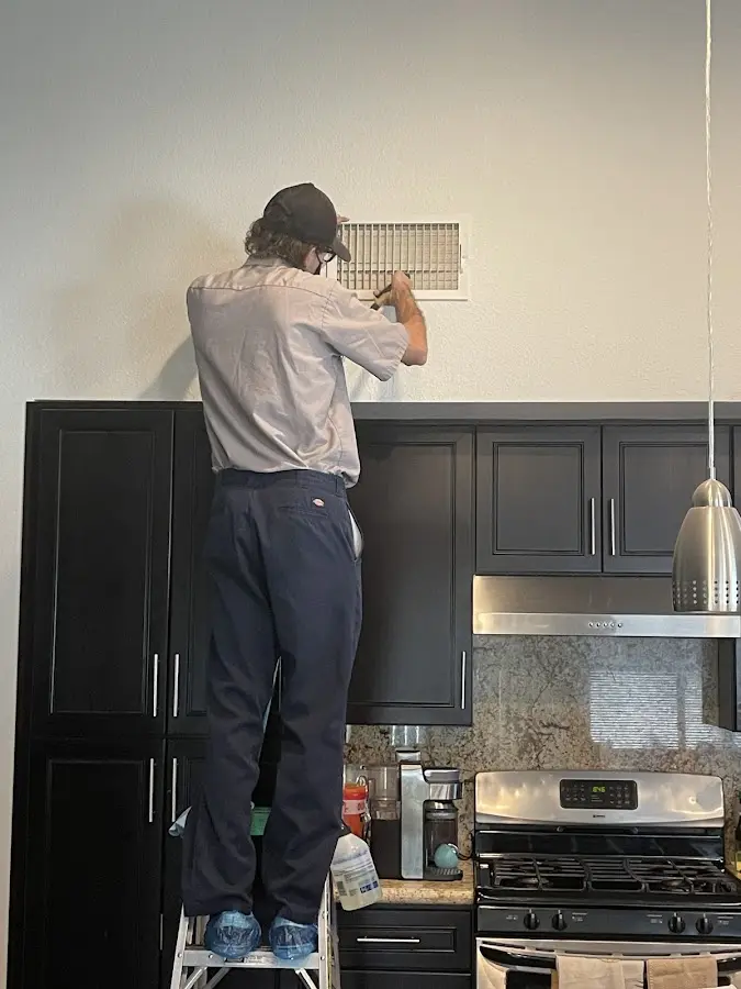 Technician inspecting an air vent during HVAC service in Danbury